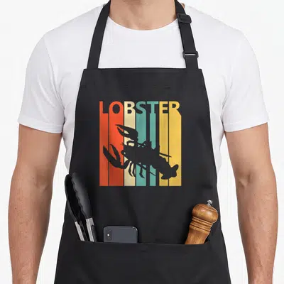Tablier de cuisine noir avec lobster gris sur fond de bandes verticales orange, crème, turquoise et jaune portant le mot lobster
