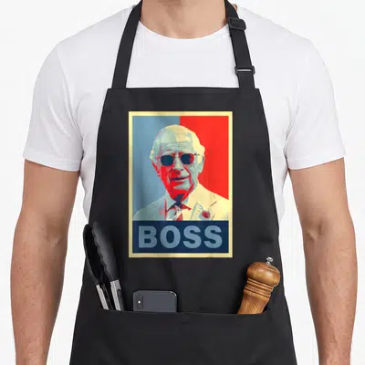 Tablier de cuisine noir avec portrait stylisé de Charles III.sunnyes et le mot Boss imprimé en bas.