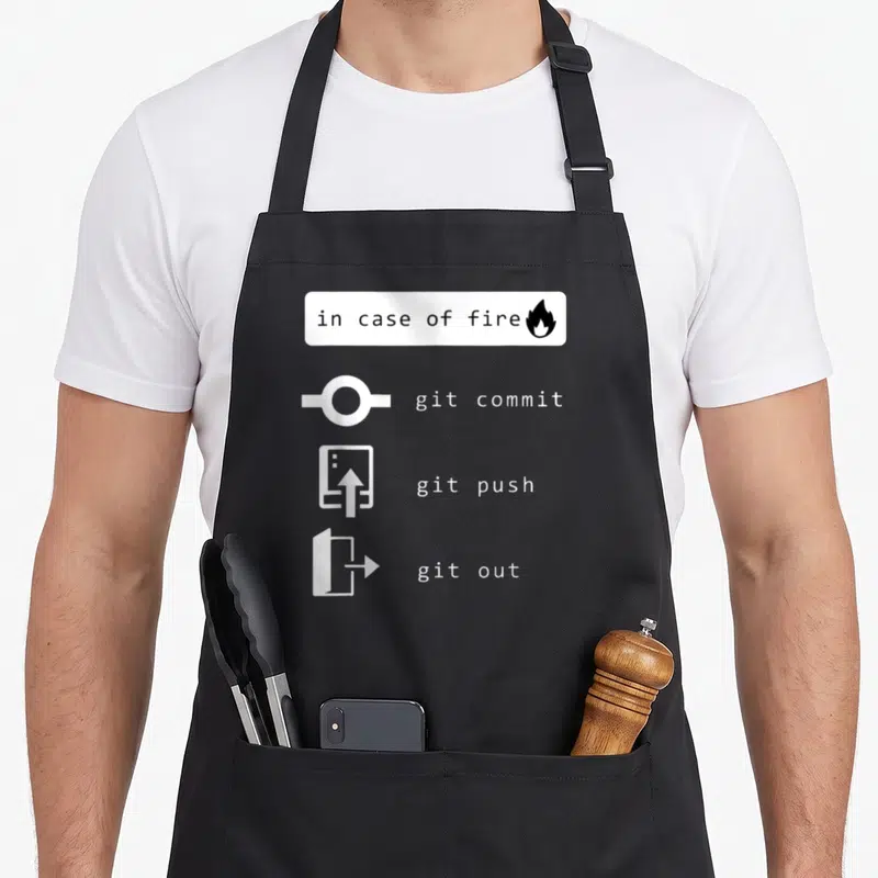 Tablier de cuisine noir avec pictogrammes blancs git commit, git push et git out sous la mention in case of fire.