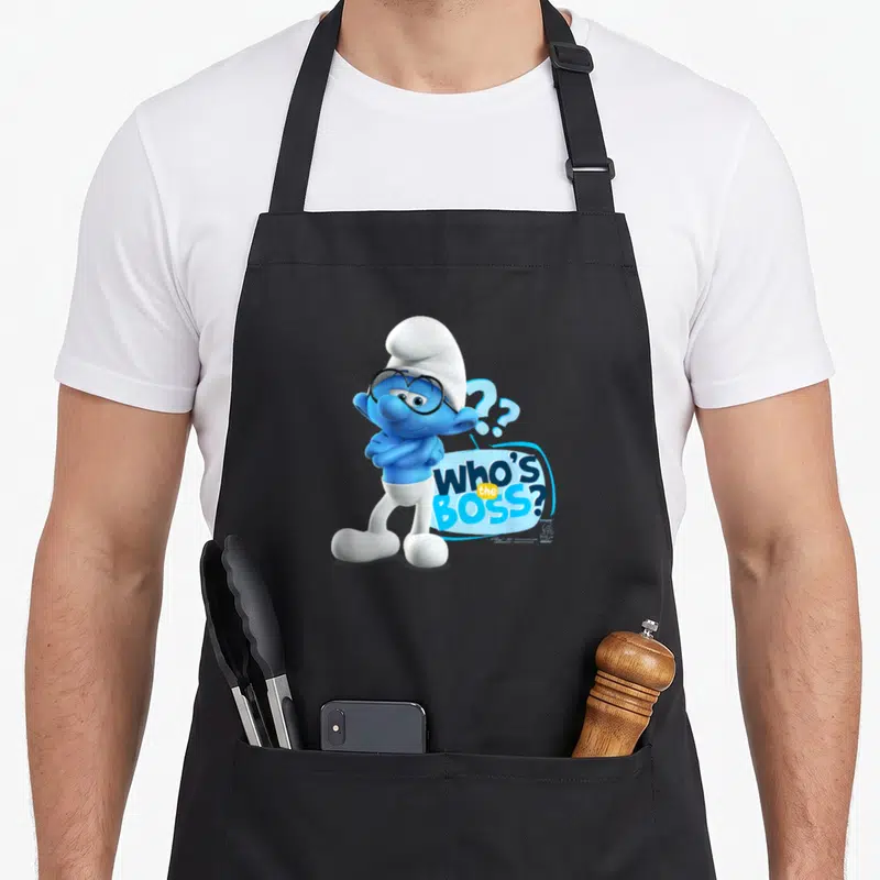 Tablier de cuisine noir avec un Schtroumpf aux lunettes et l'inscription Who's the Boss en lettres bleues et blanches.