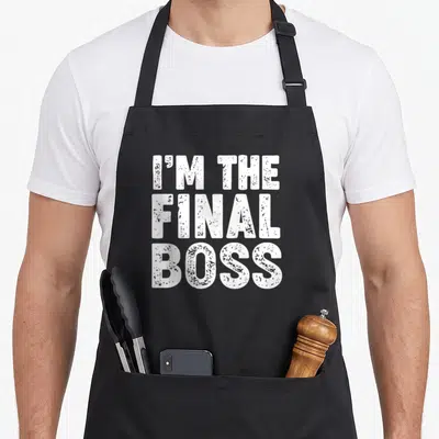 Tablier de cuisine noir avec l'inscription I'm the Final Boss en typographie blanche texturée et dégradée.