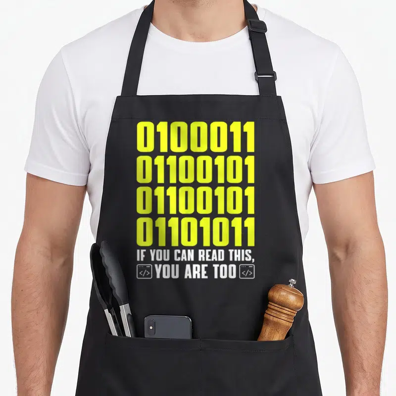 Tablier de cuisine noir avec quatre lignes de code binaire jaune et un texte blanc en anglais encadré par des icônes de balises.