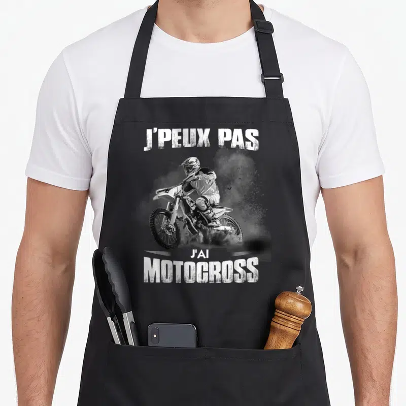 Tablier de cuisine noir avec illustration d'un pilote de motocross et le texte j'peux pas j'ai motocross en blanc.