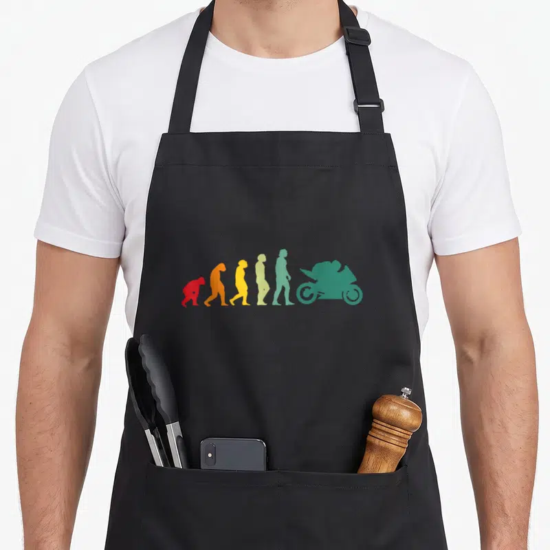 Tablier de cuisine noir avec illustration colorée de l'évolution humaine finissant par une moto de course verte.