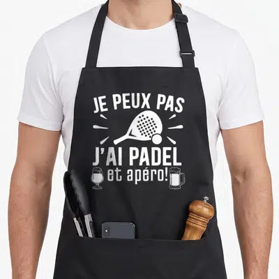 Tablier de cuisine noir avec inscription je peux pas j'ai padel et apéro illustrée d'une raquette et de deux verres.