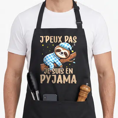 Tablier de cuisine noir avec un sloth dormant en pyjama à carreaux et texte J'peux pas je suis en pyjama.