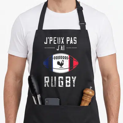 Tablier de cuisine noir avec un ballon de rugby tricolore et un coq gaulois au centre.