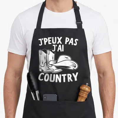 Tablier de cuisine noir avec l'inscription j'peux pas j'ai country cow-boy et un dessin de bottes et chapeau blanc.