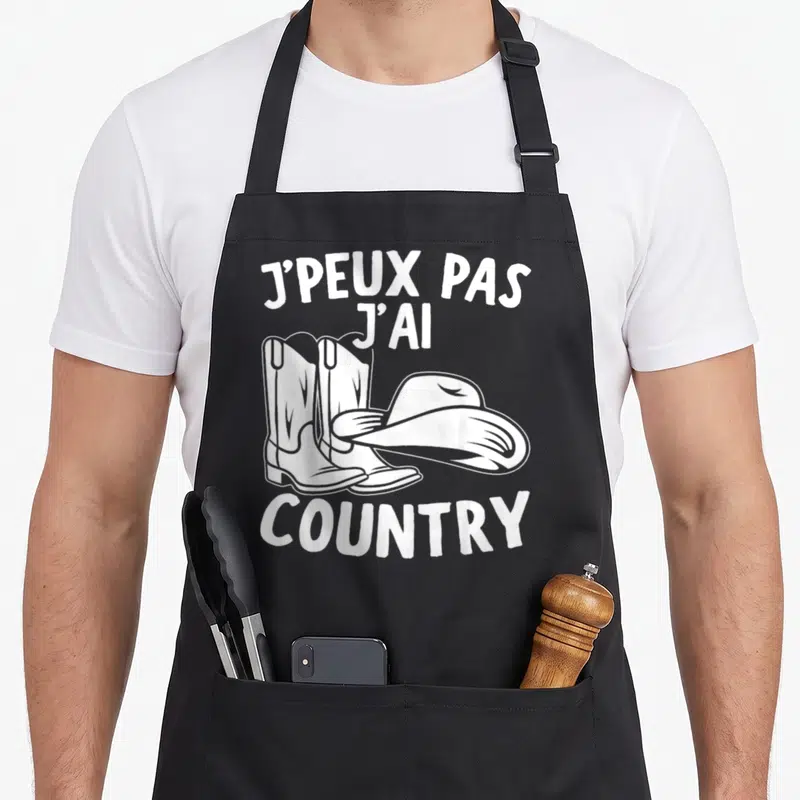 Tablier de cuisine noir avec l'inscription j'peux pas j'ai country cow-boy et un dessin de bottes et chapeau blanc.