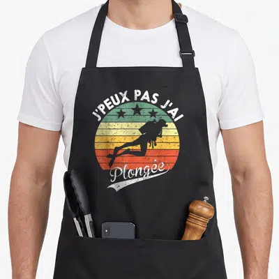 Tablier de cuisine noir avec motif circulaire vintage montrant un plongeur et le texte j'peux pas j'ai plongée en blanc.