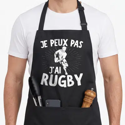 Tablier de cuisine noir avec illustration blanche d'un joueur de rugby et le texte je peux pas j'ai rugby.