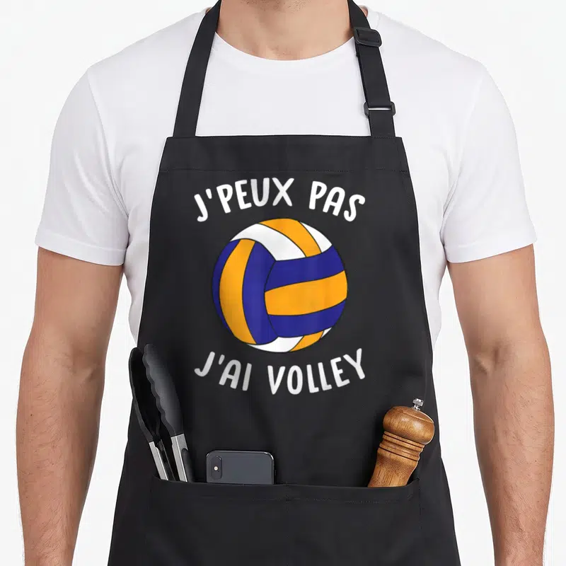 Tablier de cuisine noir avec illustration d'une balle de volley orange et bleue encadrée par un texte blanc humoristique.