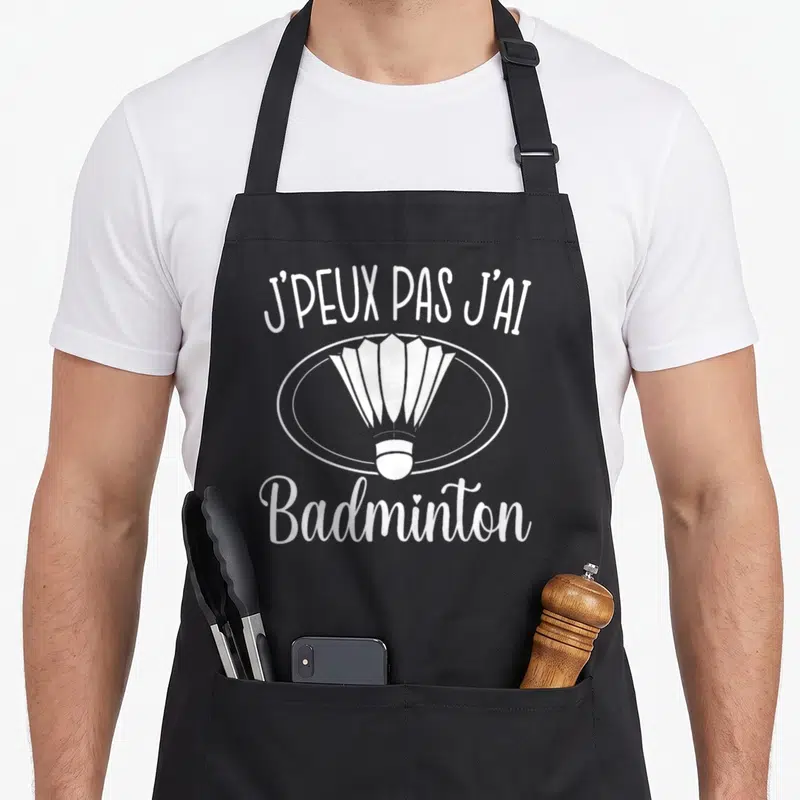 Tablier de cuisine noir avec illustration de shuttle et texte blanc J'peux pas j'ai badminton