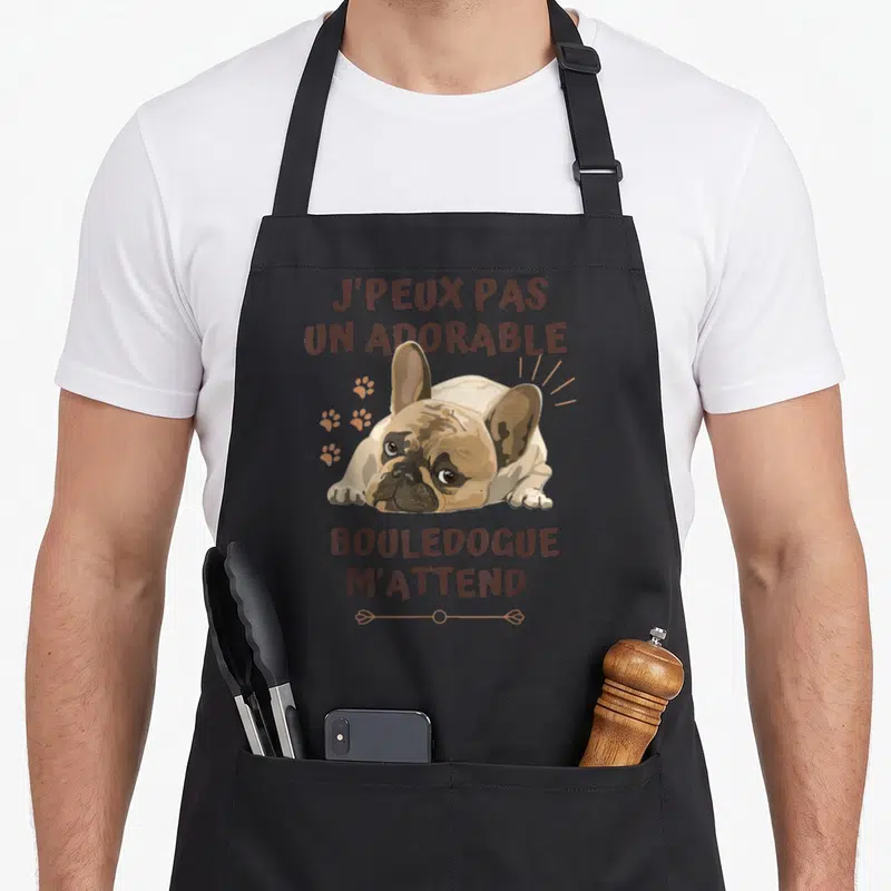 Tablier de cuisine noir avec illustration d'un bouledogue couché et texte humoristique en lettres marron.