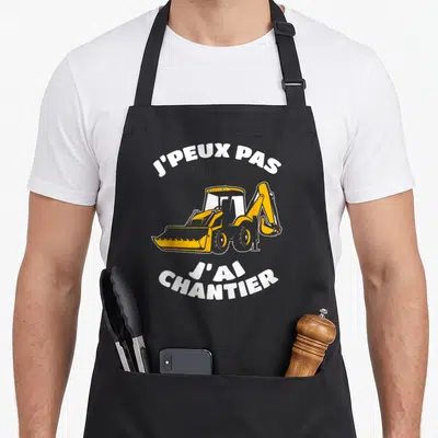 Tablier de cuisine noir avec chargeuse orange et texte blanc J'peux pas j'ai chantier