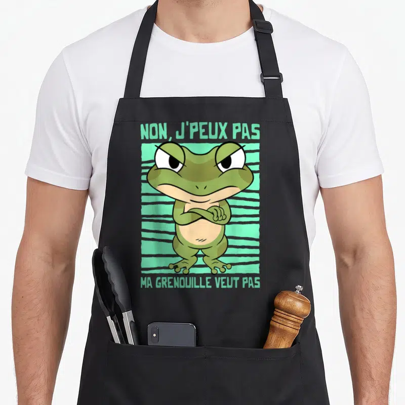 Tablier de cuisine noir avec une illustration de grenouille verte aux bras croisés et le texte non j'peux pas ma grenouille veut pas.