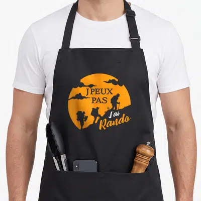 Tablier de cuisine noir avec motif circulaire orange représentant des silhouettes de randonneurs et le texte J peux pas j ai rando.