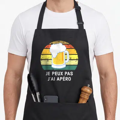 Tablier de cuisine noir avec illustration de bière et texte je peux pas j'ai apéro sur fond coloré.
