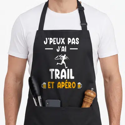Tablier de cuisine noir avec texte blanc et orange illustrant le trail et l'apéro avec des verres de bière.
