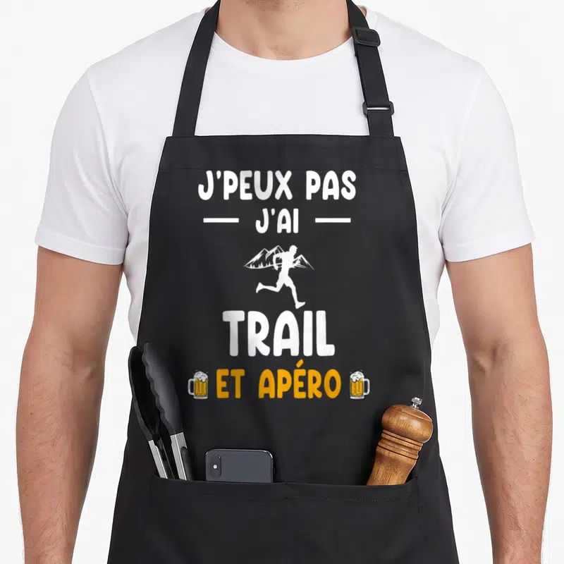 Tablier de cuisine noir avec texte blanc et orange illustrant le trail et l'apéro avec des verres de bière.