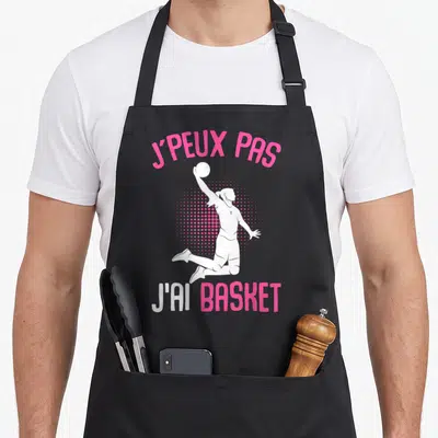 Tablier de cuisine noir avec illustration d'une basketteuse en saut et texte j'peux pas j'ai basket.