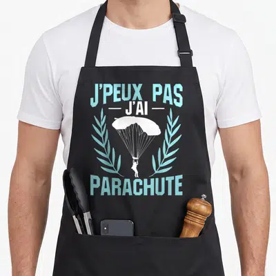 Tablier de cuisine noir avec inscription j'peux pas j'ai parachute et silhouette de parachutiste entre deux branches stylisées.