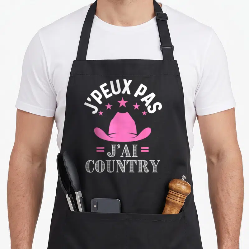 Tablier de cuisine noir avec un chapeau cowboy rose, des étoiles et le texte J'peux pas j'ai country en blanc.