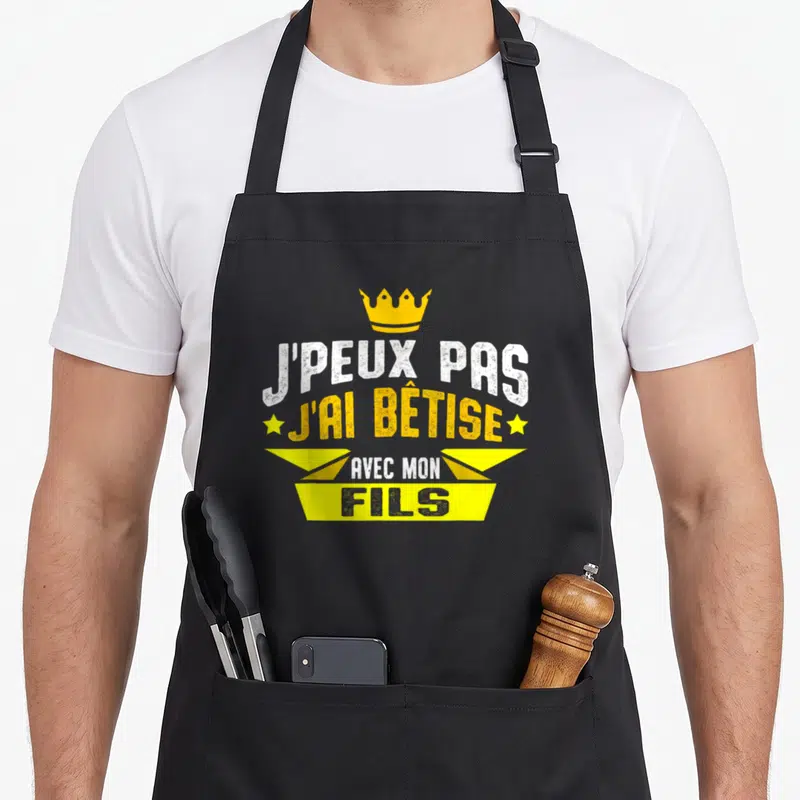 Tablier de cuisine noir avec inscription j'peux pas j'ai bêtise avec mon fils et une couronne jaune.