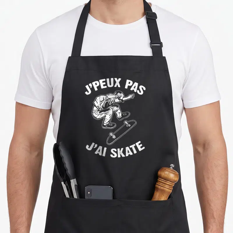 Tablier de cuisine noir avec illustration blanche d'un skateur en l'air et le texte J'PEUX PAS J'AI SKATE imprimé au centre.
