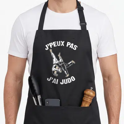 Tablier de cuisine noir avec illustration de judokas et texte j'peux pas j'ai judo en blanc.