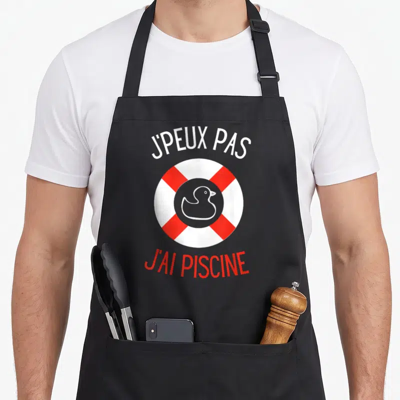 Tablier de cuisine noir avec un canard blanc dans une bouée rouge et blanche et le texte j'peux pas j'ai piscine