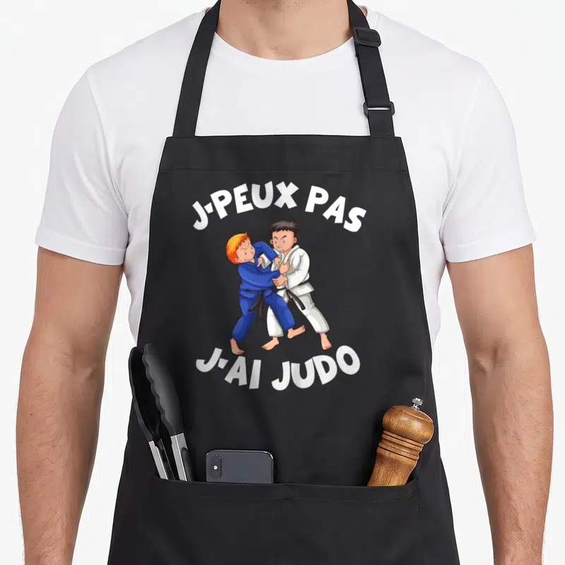 Tablier de cuisine noir avec deux enfants en judo et le texte j-peux pas j-ai judo imprimé en blanc.