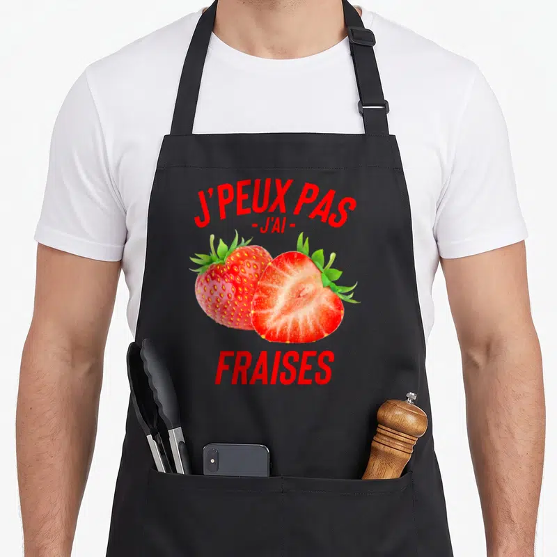 Tablier de cuisine noir avec deux fraises rouges et le texte j'peux pas j'ai fraises imprimé en rouge.