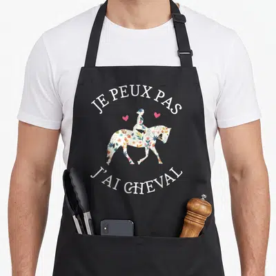 Tablier de cuisine noir avec une silhouette équestre fleurie et le texte je peux pas j'ai cheval en blanc.