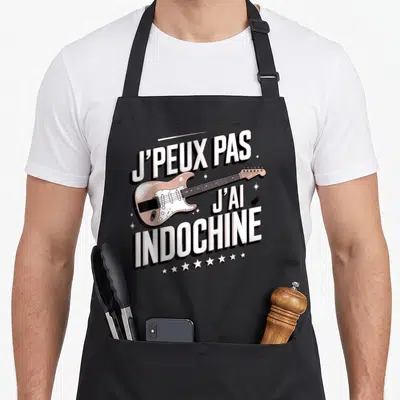 Tablier de cuisine noir avec une guitare électrique rose et le texte J'peux pas j'ai Indochine en blanc.