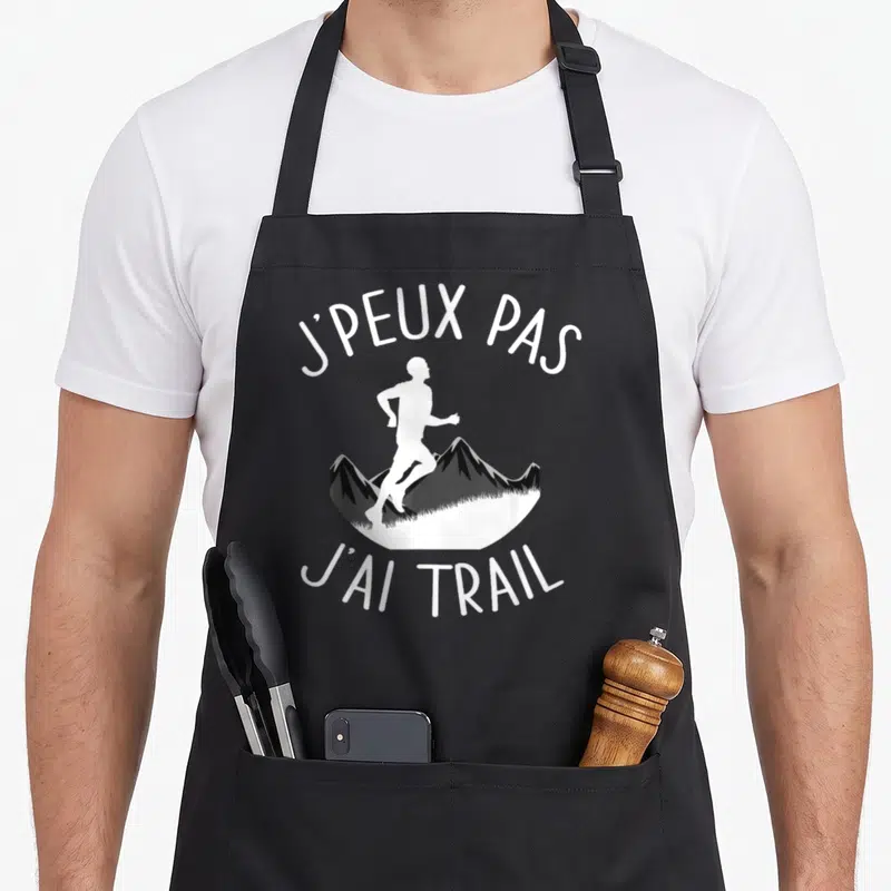 Tablier de cuisine noir avec silhouette blanche d'un coureur sur des montagnes et le texte j'peux pas j'ai trail