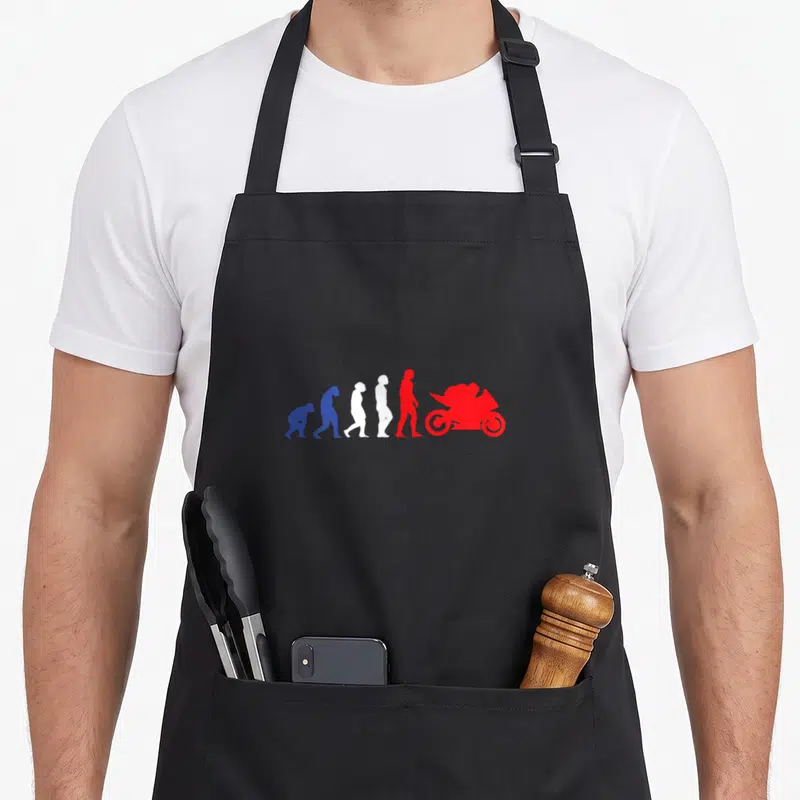Tablier de cuisine noir avec illustration colorée de l'évolution humaine finissant par une moto sport rouge.