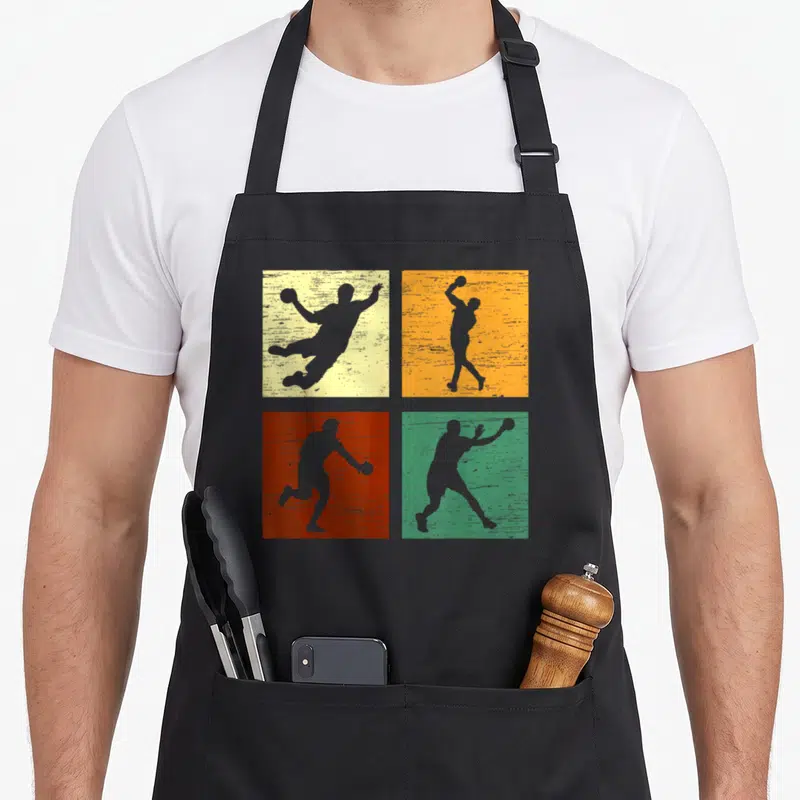 Tablier de cuisine noir avec quatre carrés colorés montrant des silhouettes de joueurs de handball en action.