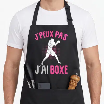 Tablier de cuisine noir avec silhouette de boxeuse blanche et texte rose J'peux pas j'ai boxe