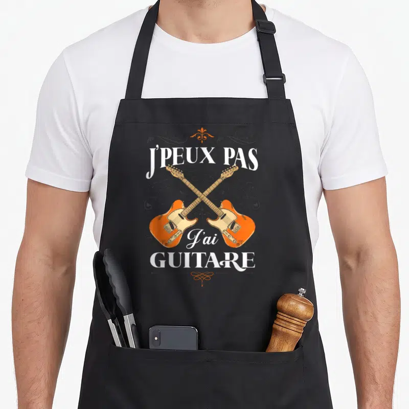 Tablier de cuisine noir avec deux guitares oranges croisées et le texte j'peux pas j'ai guitare en blanc.