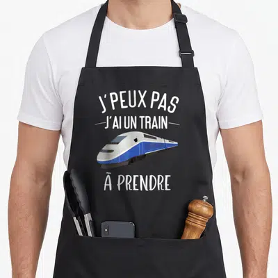 Tablier de cuisine noir avec illustration de train bleu et blanc et texte J'peux pas j'ai un train à prendre en blanc.