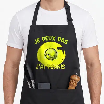 Tablier de cuisine noir avec une balle de tennis jaune et le texte je peux pas j'ai tennis en vert.
