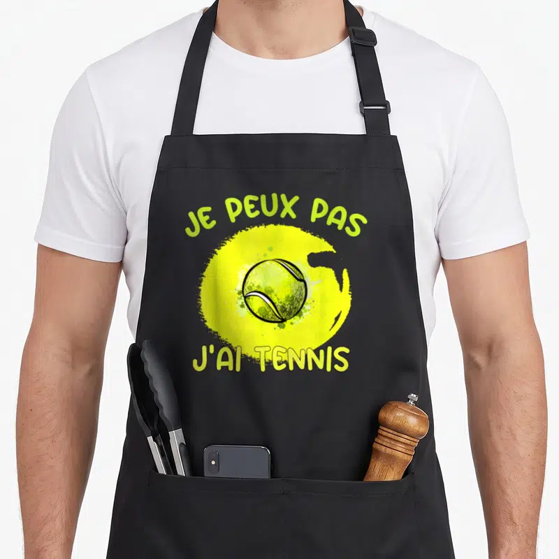 Tablier de cuisine noir avec une balle de tennis jaune et le texte je peux pas j'ai tennis en vert.