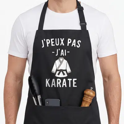 Tablier de cuisine noir avec illustration d'un gi blanc et ceinture noire sous le texte j'peux pas j'ai karate