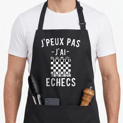 Tablier de cuisine noir avec texte blanc J'peux pas j'ai échecs et illustration de plateau de jeu.