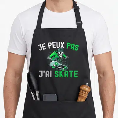 Tablier de cuisine noir avec un squelette vert sur skateboard et texte je peux pas j'ai skate