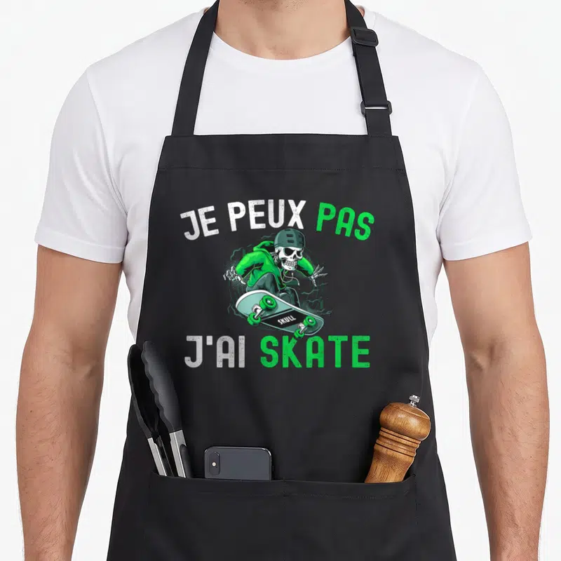 Tablier de cuisine noir avec un squelette vert sur skateboard et texte je peux pas j'ai skate