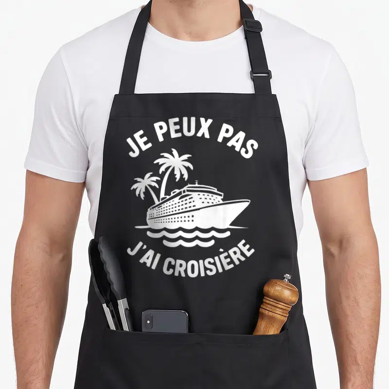 Tablier de cuisine noir avec inscription je peux pas j'ai croisière et illustration de navire de croisière entre deux palmiers.