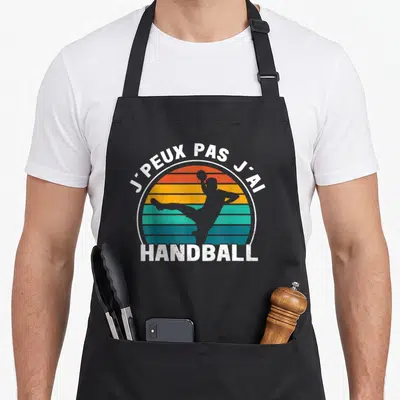 Tablier de cuisine noir avec silhouette de joueur de handball et texte j'peux pas j'ai handball en style vintage.
