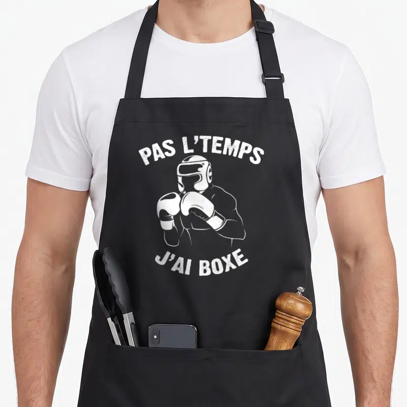 Tablier de cuisine noir avec illustration blanche d'un ring boxeur et texte humoristique sur le dos.